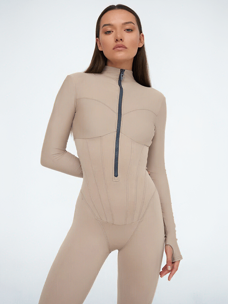 Woman wearing a beige long sleeve jumpsuit with front zipper, perfect for sports activities. Stylish, comfortable, and durable design.